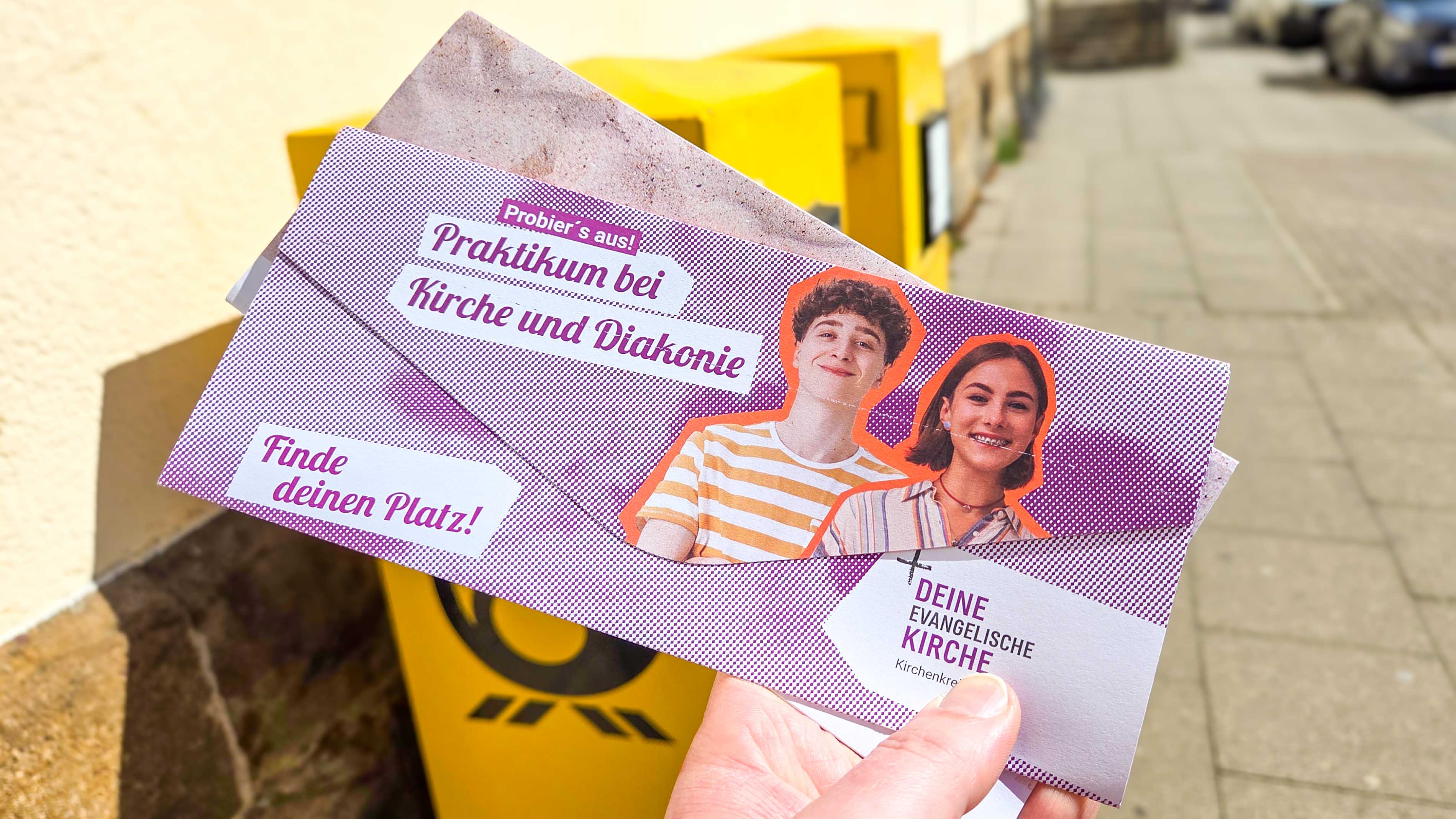 Zwei Kirchenpost-Briefe vor Briefkästen